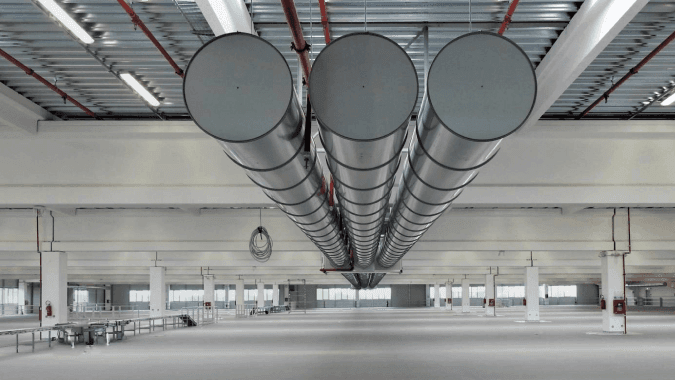 Kružni metalni ventilacioni kanali Sintra Mix-Ind instalirani na plafonu u industrijskoj hali
